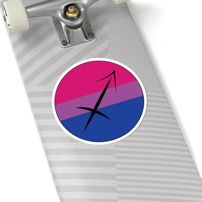 Close-up of the bottom of a silver skateboard featuring a 6 inch by 6 inch circular zodiac sticker with a centered Sagittarius glyph on a Bisexual pride flag style background applied to the surface.