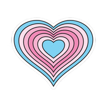 Heart-shaped transfeminine pride flag sticker featuring nested heart stripes in light blue, pale pink, light pink, pink, light pink, pale pink, and light blue, outlined with a thin black border and a white sticker border. The sticker is shown on a white background.