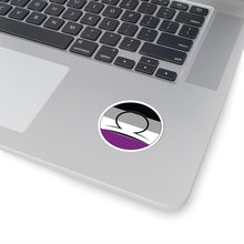 Close-up of the bottom right corner of a silver laptop featuring a 2 inch by 2 inch circular zodiac sticker with a centered Libra glyph on an Asexual pride flag style background applied to the surface.