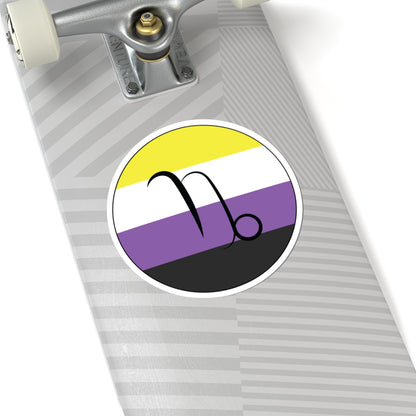 Close-up of the bottom of a silver skateboard featuring a 6 inch by 6 inch circular zodiac sticker with a centered Capricorn glyph on a Nonbinary pride flag style background applied to the surface.