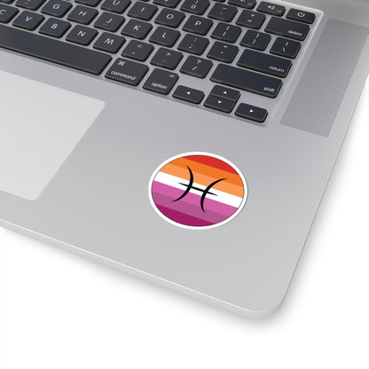 Close-up of the bottom right corner of a silver laptop featuring a 2 inch by 2 inch circular zodiac sticker with a centered Pisces glyph on a Lesbian pride flag style background applied to the surface.