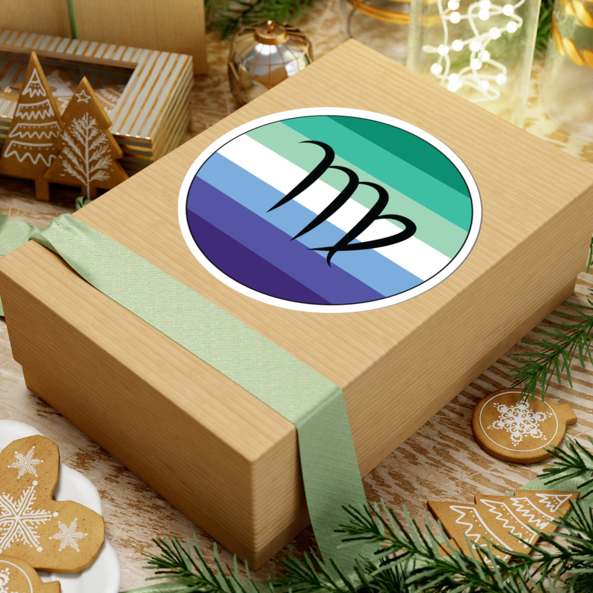 Gift box with a green ribbon on a festive background with cookies and Christmas decorations. Virgo Gay Men pride sticker centered on the box.