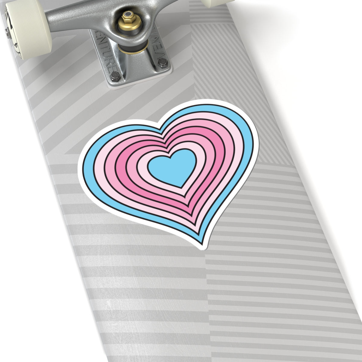 Close-up of the bottom of a silver skateboard featuring a 6 inch by 6 inch pride flag heart sticker in a Transfem flag style applied to the surface.