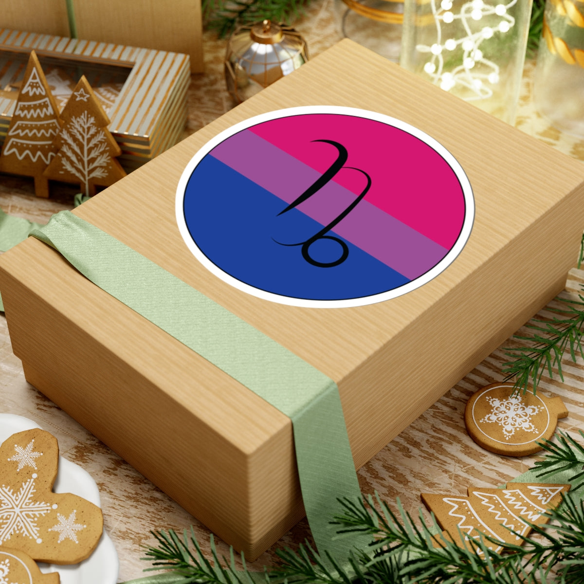 Gift box with a green ribbon on a festive background with cookies and Christmas decorations. Capricorn Bisexual pride sticker centered on the box.