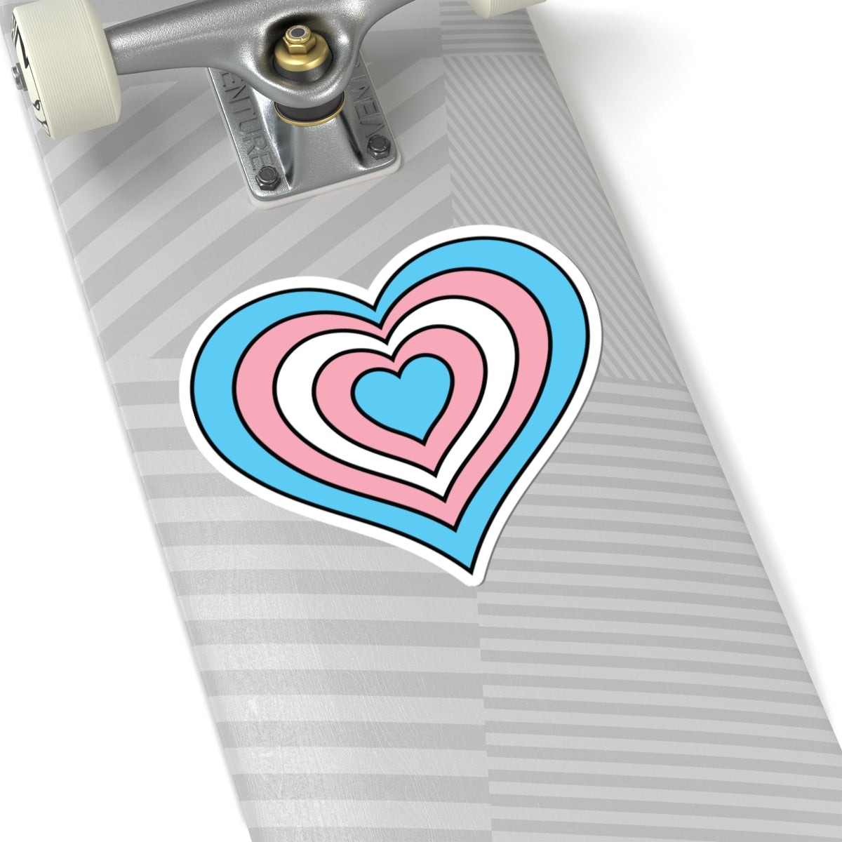 Close-up of the bottom of a silver skateboard featuring a 6 inch by 6 inch pride flag heart sticker in a Transgender flag style applied to the surface.