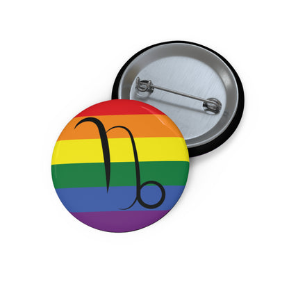 Front and back view of a circular rainbow pride flag button featuring the Capricorn zodiac symbol in black centered on the front.