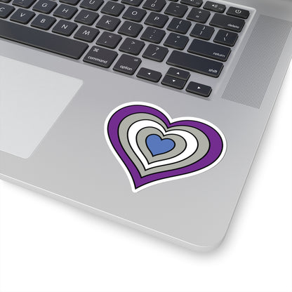 Close-up of the bottom right corner of a silver laptop featuring a 3 inch by 3 inch pride flag heart sticker in a Greysexual flag style applied to the surface.