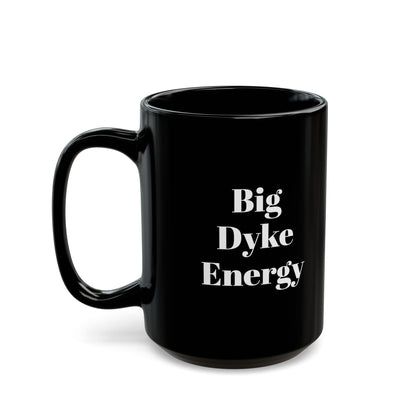 A black mug with the words "Big Dyke Energy" printed in white letters on the side facing outward if the mug is held by the handle in the right hand. The image of the mug is shown on a white background.