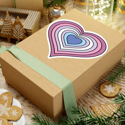 Gift box with a green ribbon on a festive background with cookies and Christmas decorations. Heart-shaped Bigender pride sticker centered on the box.