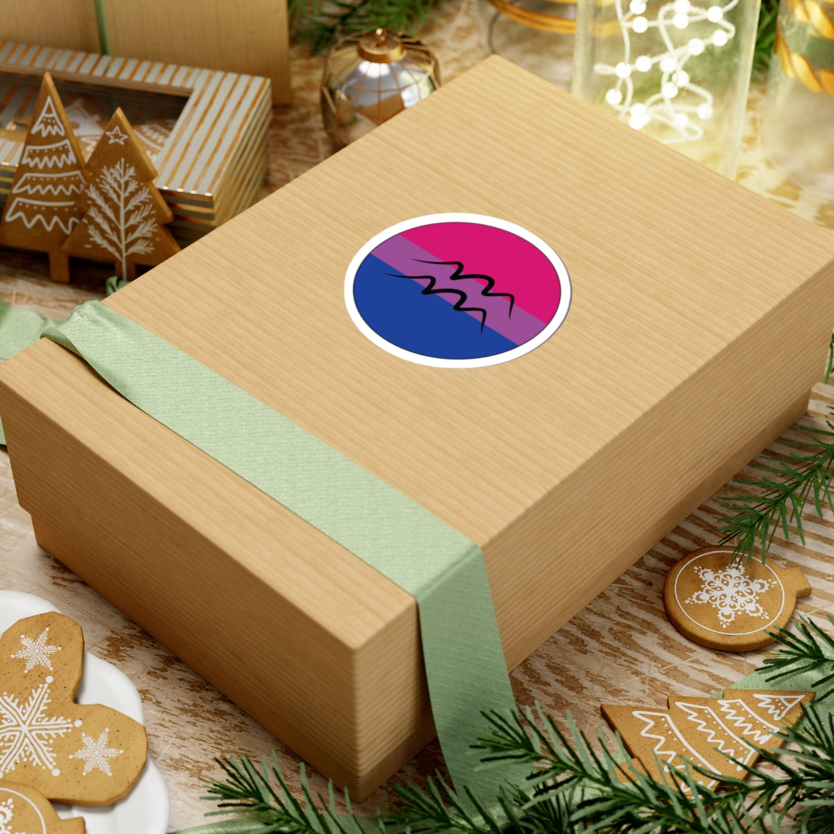 Gift box with a green ribbon on a festive background with cookies and Christmas decorations. Aquarius Bisexual pride sticker centered on the box.