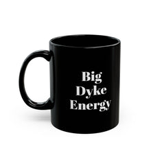 A black mug with the words "Big Dyke Energy" printed in white letters on the side facing outward if the mug is held by the handle in the right hand. The image of the mug is shown on a white background.