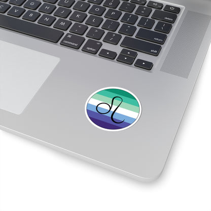 Close-up of the bottom right corner of a silver laptop featuring a 2 inch by 2 inch circular zodiac sticker with a centered Leo glyph on a Gay Men pride flag style background applied to the surface.