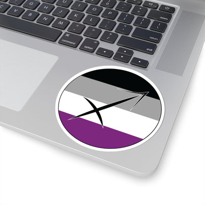 Close-up of the bottom right corner of a silver laptop featuring a 4 inch by 4 inch circular zodiac sticker with a centered Sagittarius glyph on an Asexual pride flag style background applied to the surface.