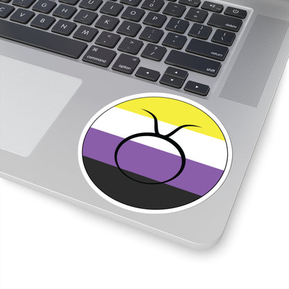 Close-up of the bottom right corner of a silver laptop featuring a 4 inch by 4 inch circular zodiac sticker with a centered Taurus glyph on a Nonbinary pride flag style background applied to the surface.