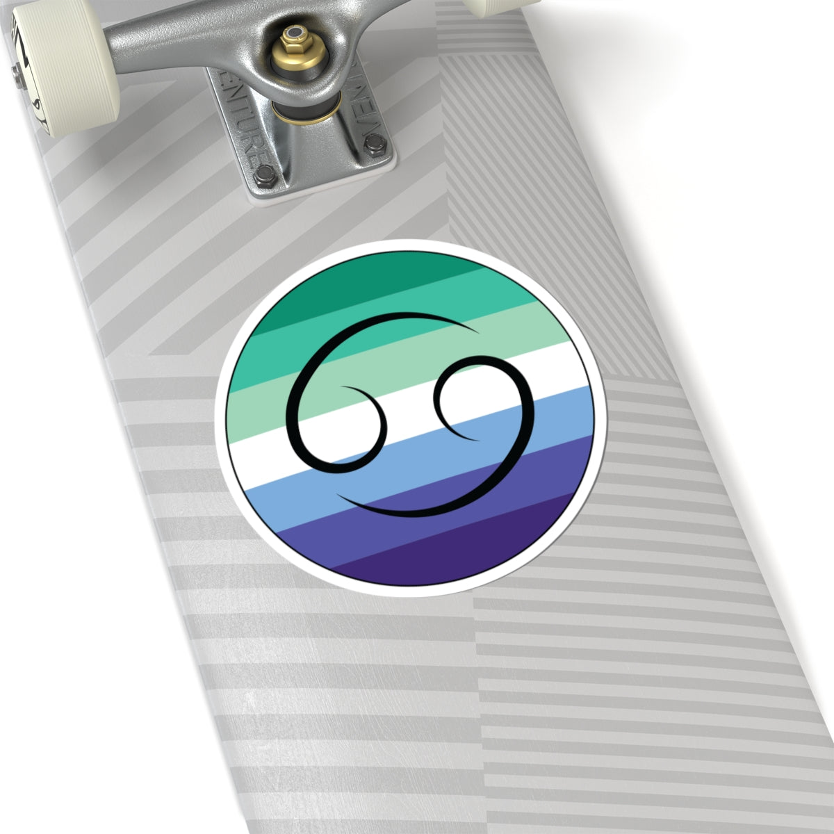 Close-up of the bottom of a silver skateboard featuring a 6 inch by 6 inch circular zodiac sticker with a centered Cancer glyph on a Gay Men pride flag style background applied to the surface.