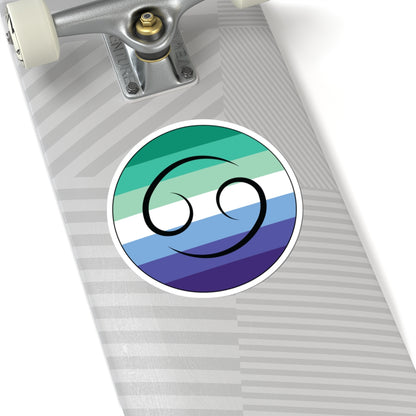 Close-up of the bottom of a silver skateboard featuring a 6 inch by 6 inch circular zodiac sticker with a centered Cancer glyph on a Gay Men pride flag style background applied to the surface.