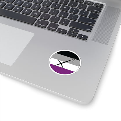 Close-up of the bottom right corner of a silver laptop featuring a 2 inch by 2 inch circular zodiac sticker with a centered Sagittarius glyph on an Asexual pride flag style background applied to the surface.