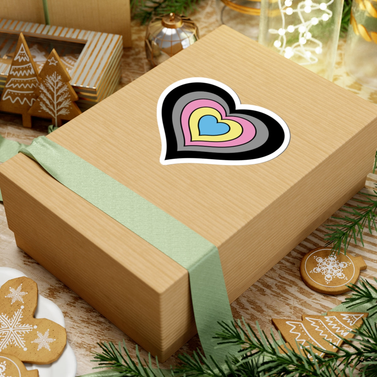 Gift box with a green ribbon on a festive background with cookies and Christmas decorations. Heart-shaped Polygender pride sticker centered on the box.