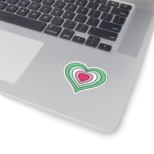 Close-up of the bottom right corner of a silver laptop featuring a 2 inch by 2 inch pride flag heart sticker in an Abrosexual flag style applied to the surface.