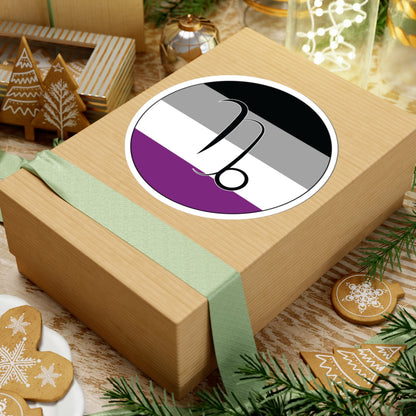 Gift box with a green ribbon on a festive background with cookies and Christmas decorations. Capricorn Asexual pride sticker centered on the box.