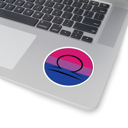 Close-up of the bottom right corner of a silver laptop featuring a 3 inch by 3 inch circular zodiac sticker with a centered Libra glyph on a Bisexual pride flag style background applied to the surface.