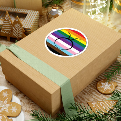 Gift box with a green ribbon on a festive background with cookies and Christmas decorations. Taurus Progress pride sticker centered on the box.