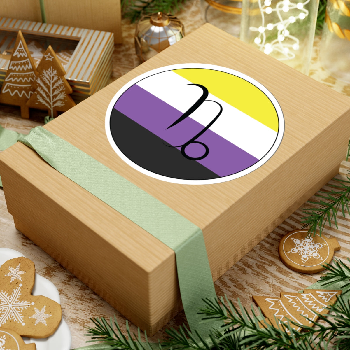 Gift box with a green ribbon on a festive background with cookies and Christmas decorations. Capricorn Nonbinary pride sticker centered on the box.