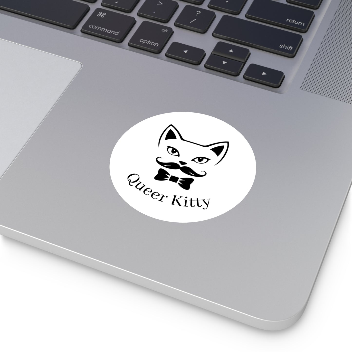 Laptop with a sticker featuring a cat face with a mustache and bow tie and the text 'Queer Kitty'.