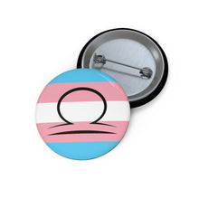 Front and back view of a circular transgender pride flag button featuring the Libra zodiac symbol in black centered on the front.