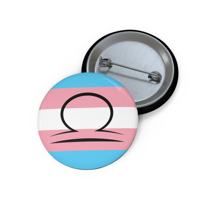 Front and back view of a circular transgender pride flag button featuring the Libra zodiac symbol in black centered on the front.