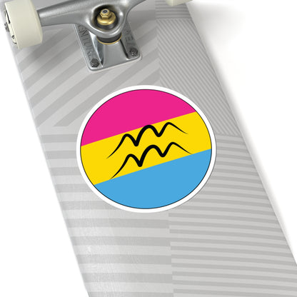 Close-up of the bottom right corner of a silver laptop featuring a 6 inch by 6 inch circular zodiac sticker with a centered Aquarius glyph on a Pansexual pride flag style background applied to the surface.