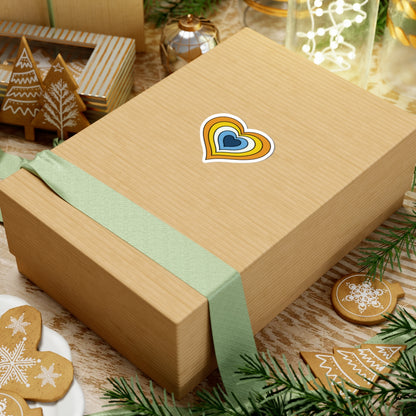 Gift box with a green ribbon on a festive background with cookies and Christmas decorations. Heart-shaped Aroace pride sticker centered on the box.