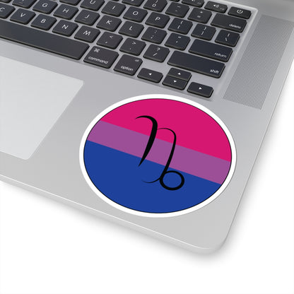 Close-up of the bottom right corner of a silver laptop featuring a 4 inch by 4 inch circular zodiac sticker with a centered Capricorn glyph on a Bisexual pride flag style background applied to the surface.