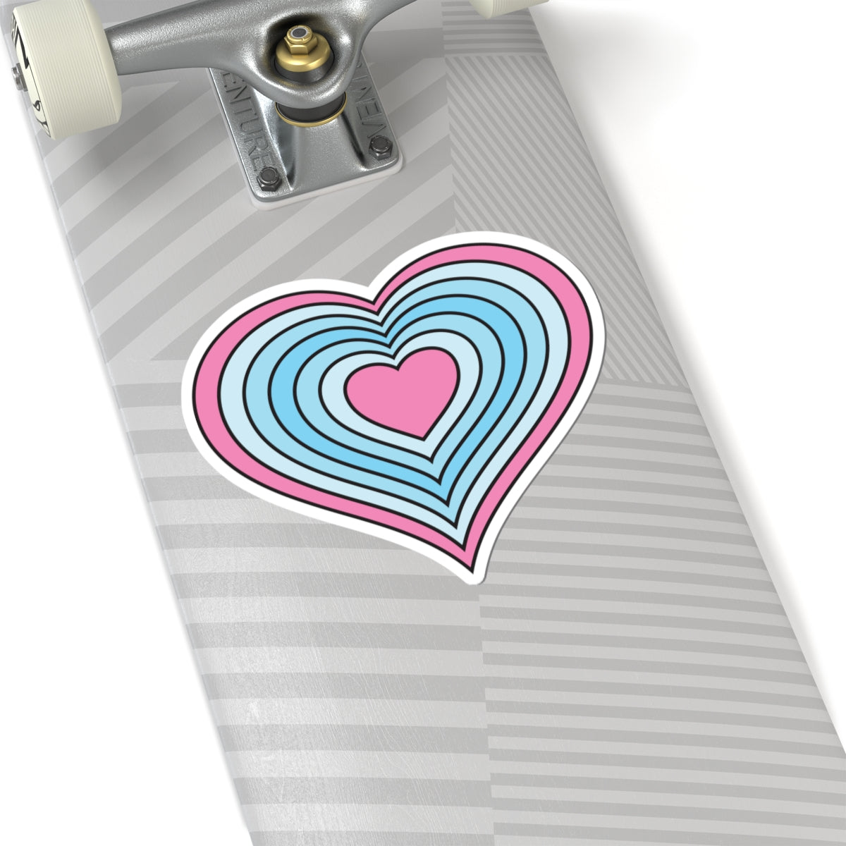 Close-up of the bottom of a silver skateboard featuring a 6 inch by 6 inch pride flag heart sticker in a Transmasc flag style applied to the surface.