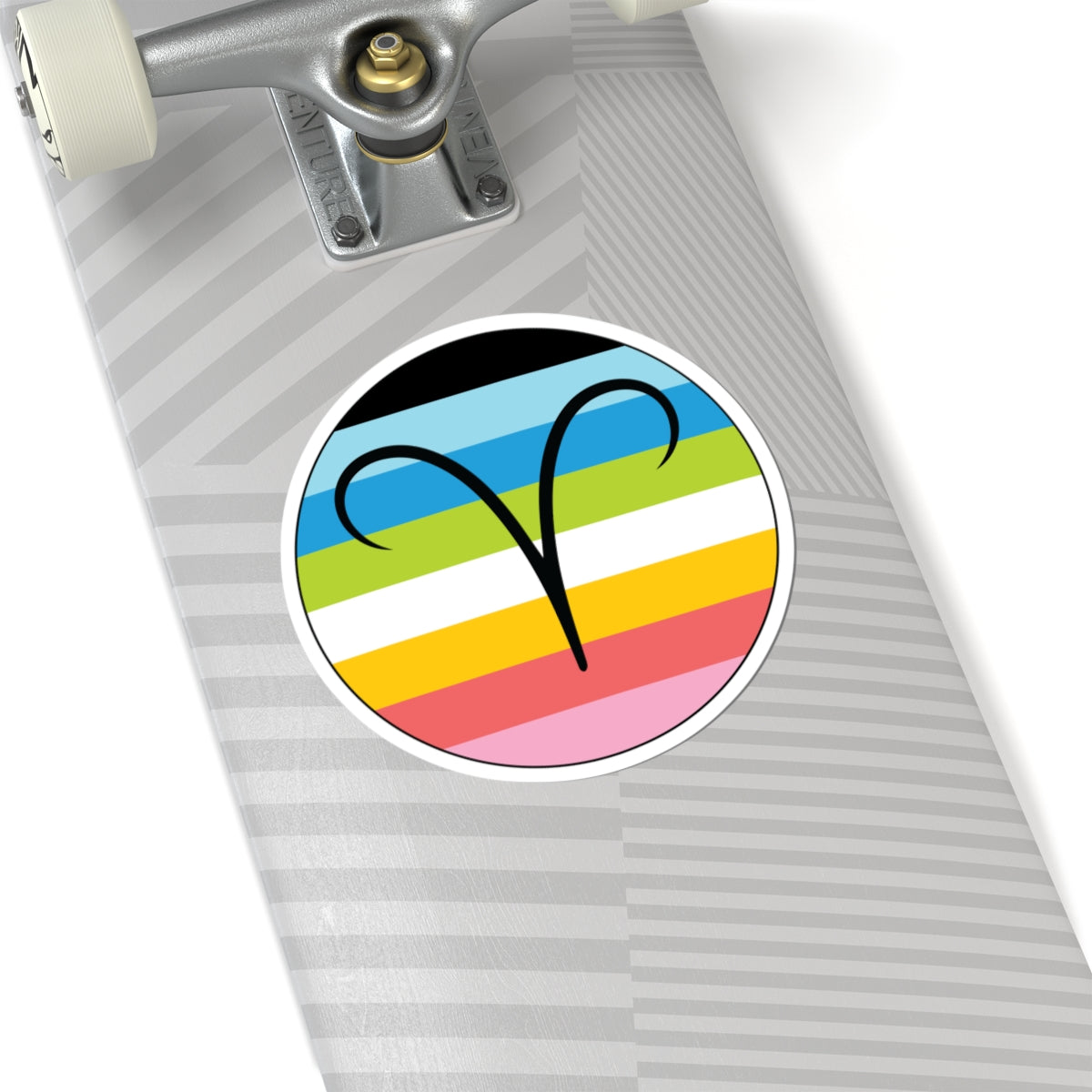 Close-up of the bottom of a silver skateboard featuring a 6 inch by 6 inch circular zodiac sticker with a centered Aires glyph on a Queer pride flag style background applied to the surface.