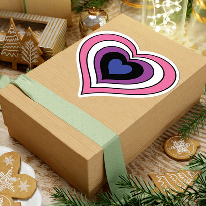 Gift box with a green ribbon on a festive background with cookies and Christmas decorations. Heart-shaped Genderfluid pride sticker centered on the box.