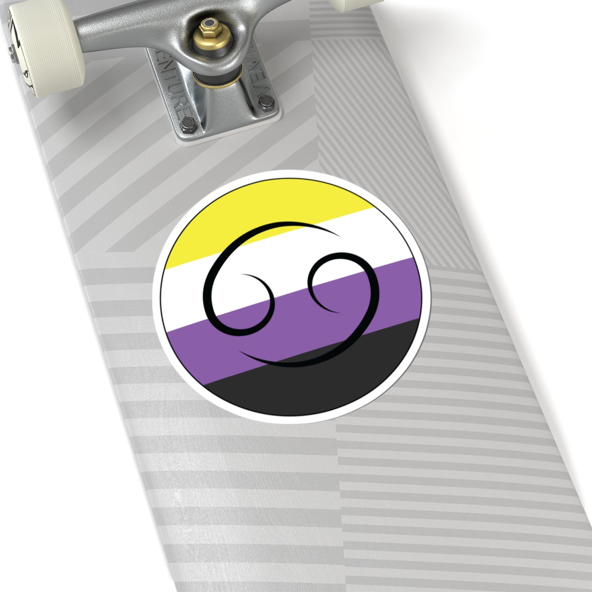 Close-up of the bottom of a silver skateboard featuring a 6 inch by 6 inch circular zodiac sticker with a centered Leo glyph on a Nonbinary pride flag style background applied to the surface.