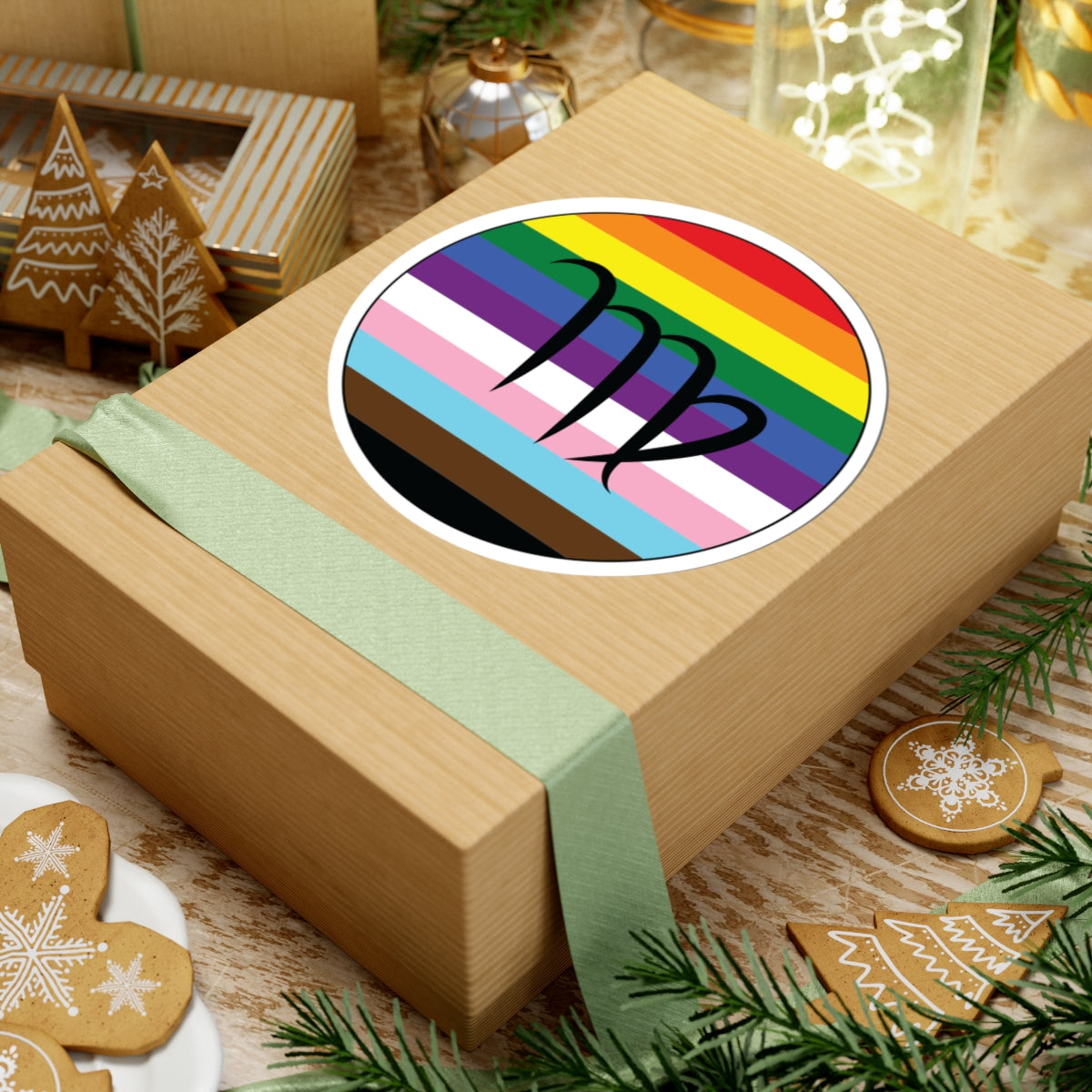 Gift box with a green ribbon on a festive background with cookies and Christmas decorations. Virgo Progress pride sticker centered on the box.
