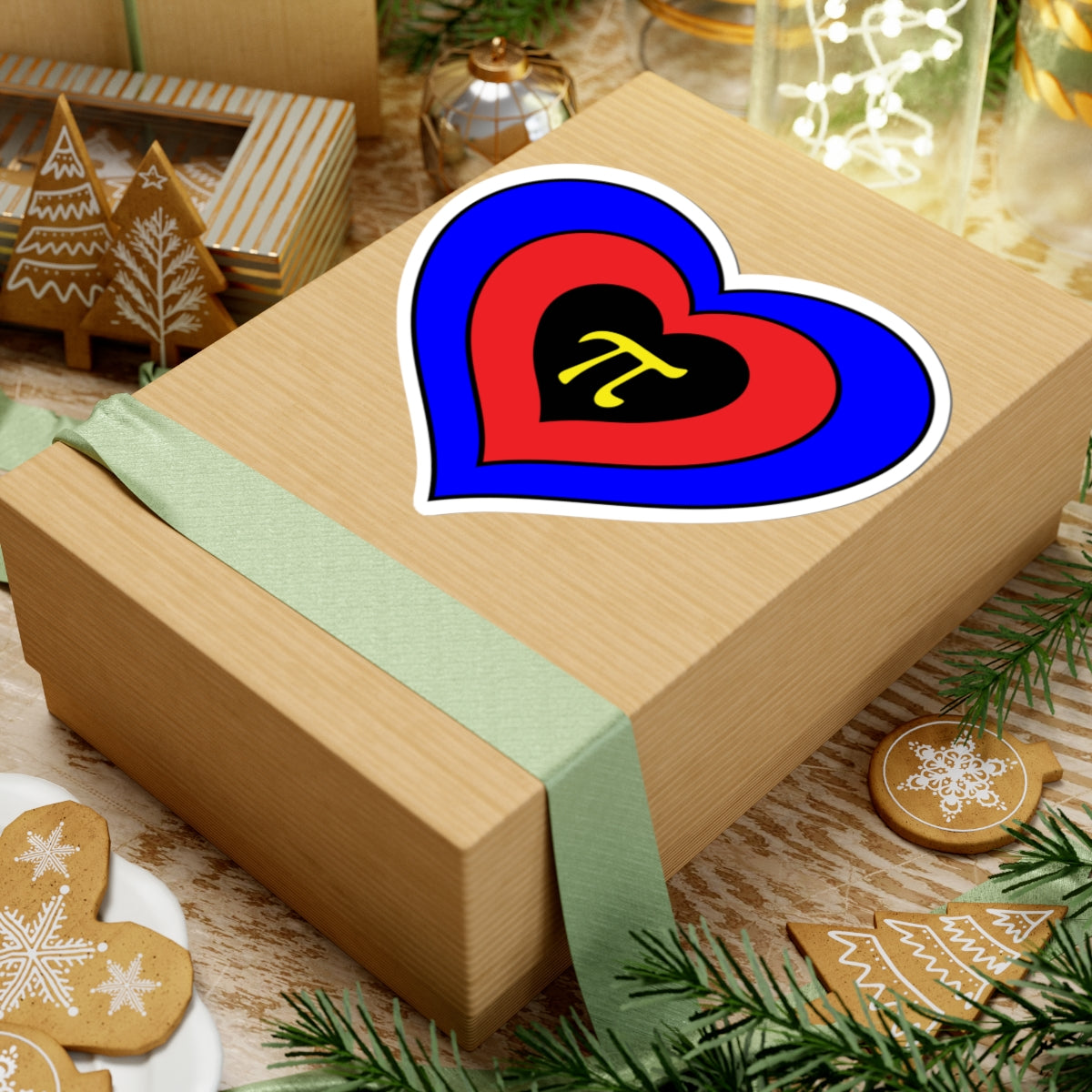 Gift box with a green ribbon on a festive background with cookies and Christmas decorations. Heart-shaped Polyamory pride sticker centered on the box.