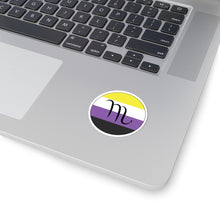 Close-up of the bottom right corner of a silver laptop featuring a 2 inch by 2 inch circular zodiac sticker with a centered Scorpio glyph on an Nonbinary pride flag style background applied to the surface.