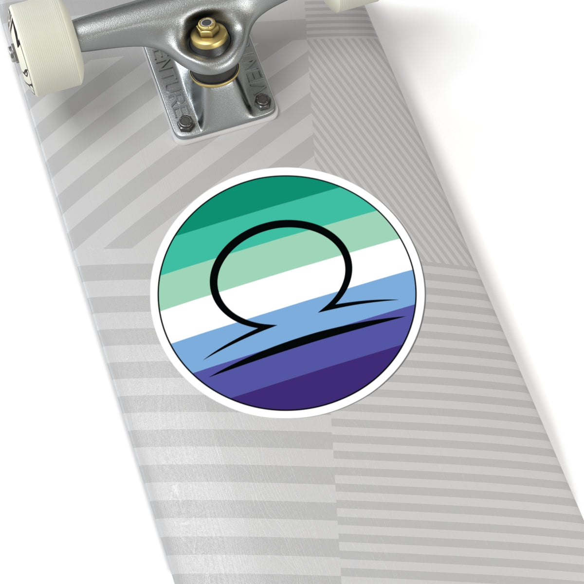 Close-up of the bottom right corner of a silver laptop featuring a 6 inch by 6 inch circular zodiac sticker with a centered Libra glyph on a Gay Men pride flag style background applied to the surface.
