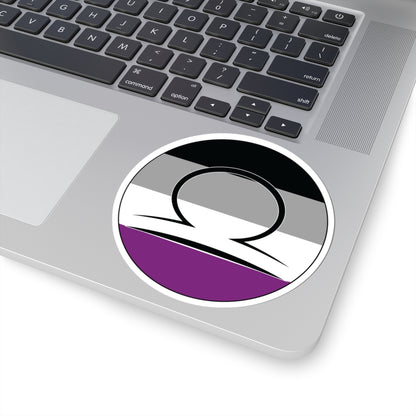 Close-up of the bottom right corner of a silver laptop featuring a 4 inch by 4 inch circular zodiac sticker with a centered Libra glyph on an Asexual pride flag style background applied to the surface.