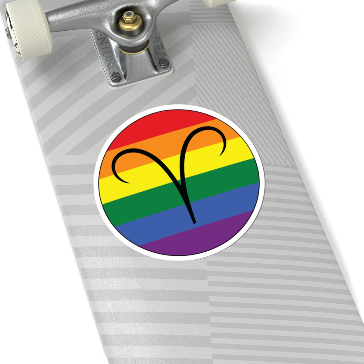 Close-up of the bottom of a silver skateboard featuring a 6 inch by 6 inch circular zodiac sticker with a centered Aires glyph on a Rainbow pride flag style background applied to the surface.