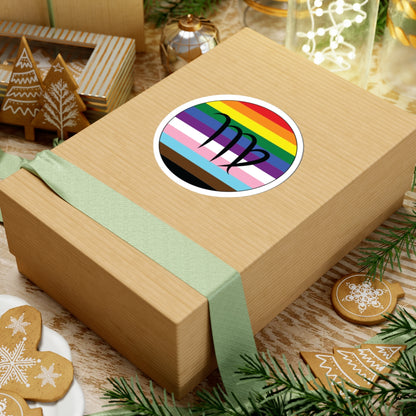 Gift box with a green ribbon on a festive background with cookies and Christmas decorations. Virgo Progress pride sticker centered on the box.