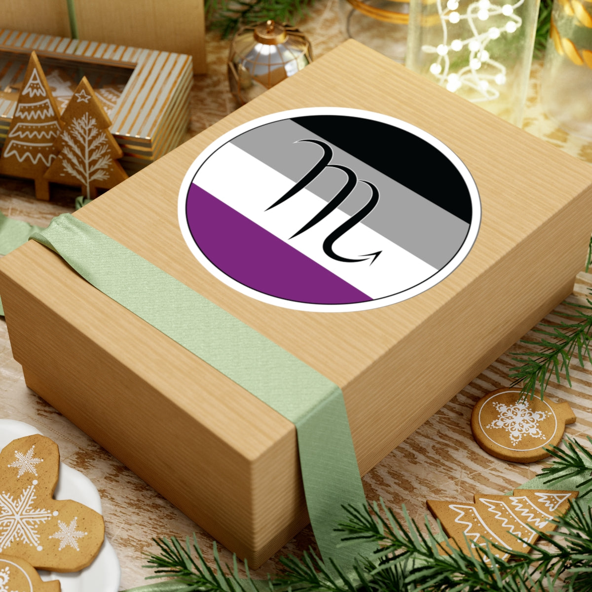 Gift box with a green ribbon on a festive background with cookies and Christmas decorations. Scorpio Asexual pride sticker centered on the box.