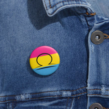 Close-up of a white circular pride button featuring the Libra zodiac glyph centered over a Pansexual pride flag background in pink, yellow, and blue, attached to a blue denim jacket at the right chest with the button clearly visible.