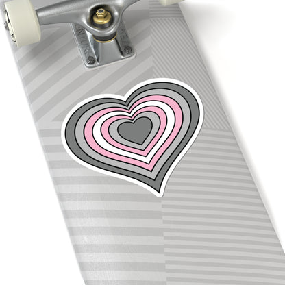 Close-up of the bottom of a silver skateboard featuring a 6 inch by 6 inch pride flag heart sticker in a Demigirl flag style applied to the surface.