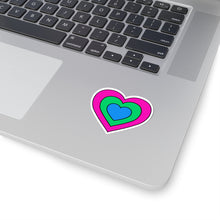 Close-up of the bottom right corner of a silver laptop featuring a 2 inch by 2 inch pride flag heart sticker in a Polysexual flag style applied to the surface.