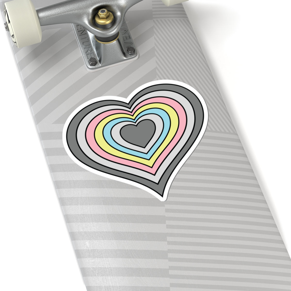 Close-up of the bottom of a silver skateboard featuring a 6 inch by 6 inch pride flag heart sticker in a Demiflux flag style applied to the surface.