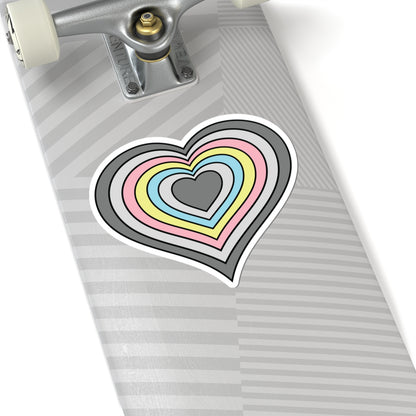 Close-up of the bottom of a silver skateboard featuring a 6 inch by 6 inch pride flag heart sticker in a Demiflux flag style applied to the surface.